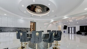 Un interior moderno con una mesa de comedor redonda, sillas tapizadas de color negro y detalles dorados.