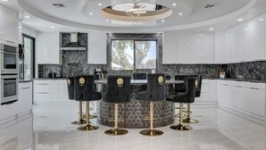 Una cocina moderna con una isla central, muebles blancos y un diseño de techo circular.