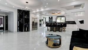 Una cocina amplia y moderna con electrodomésticos elegantes, una isla central y un comedor con sillas negras.