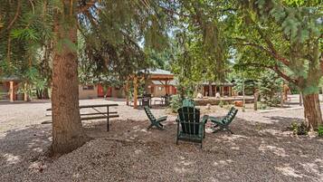 A rustic outdoor seating area with Adirondack chairs, a picnic table, and a wooden gazebo.