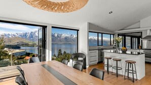 Eine moderne Küche mit einer großen Kochinsel, Barhocker und Blick auf Berge und See.