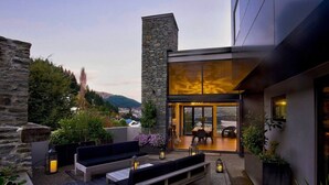 Eine moderne Außenpatio mit Steinmauern, einer Sitzgelegenheit und einem verglasten Essbereich mit Blick auf die umliegende Landschaft.