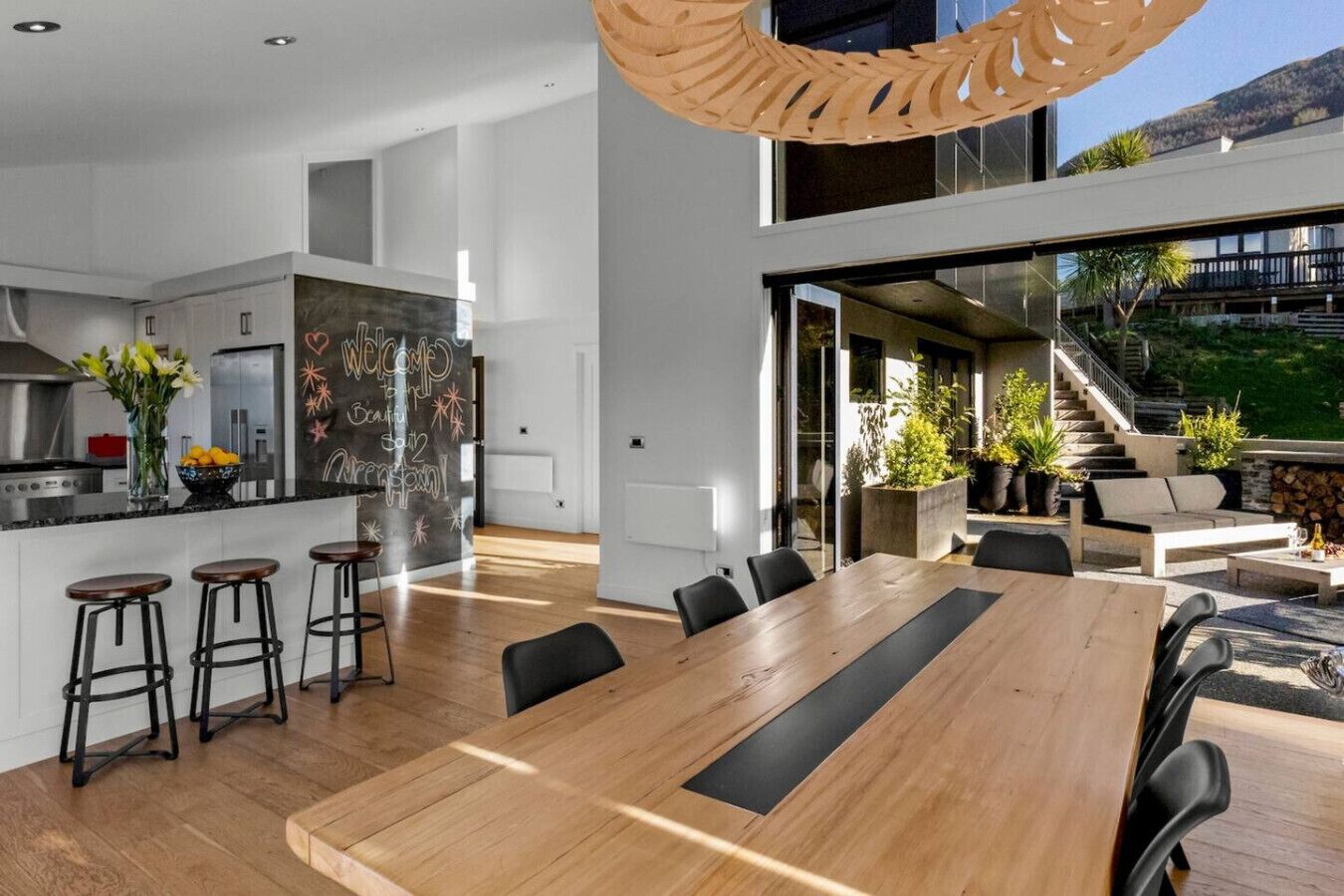 A modern kitchen with a large island, bar stools, and a chalkboard wall.