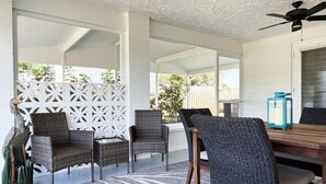 A covered patio area with wicker furniture, a dining table, and a ceiling fan. - Coastal Chic 2BR – Modern Stay Near Manasota Key (Englewood)