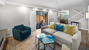 A modern living room with a sofa, a teal armchair, and a glass coffee table.
