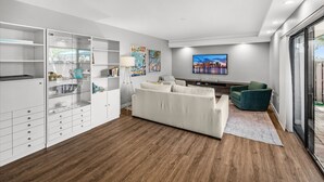 A modern living room with a white sofa, a green armchair, and a TV mounted on the wall.