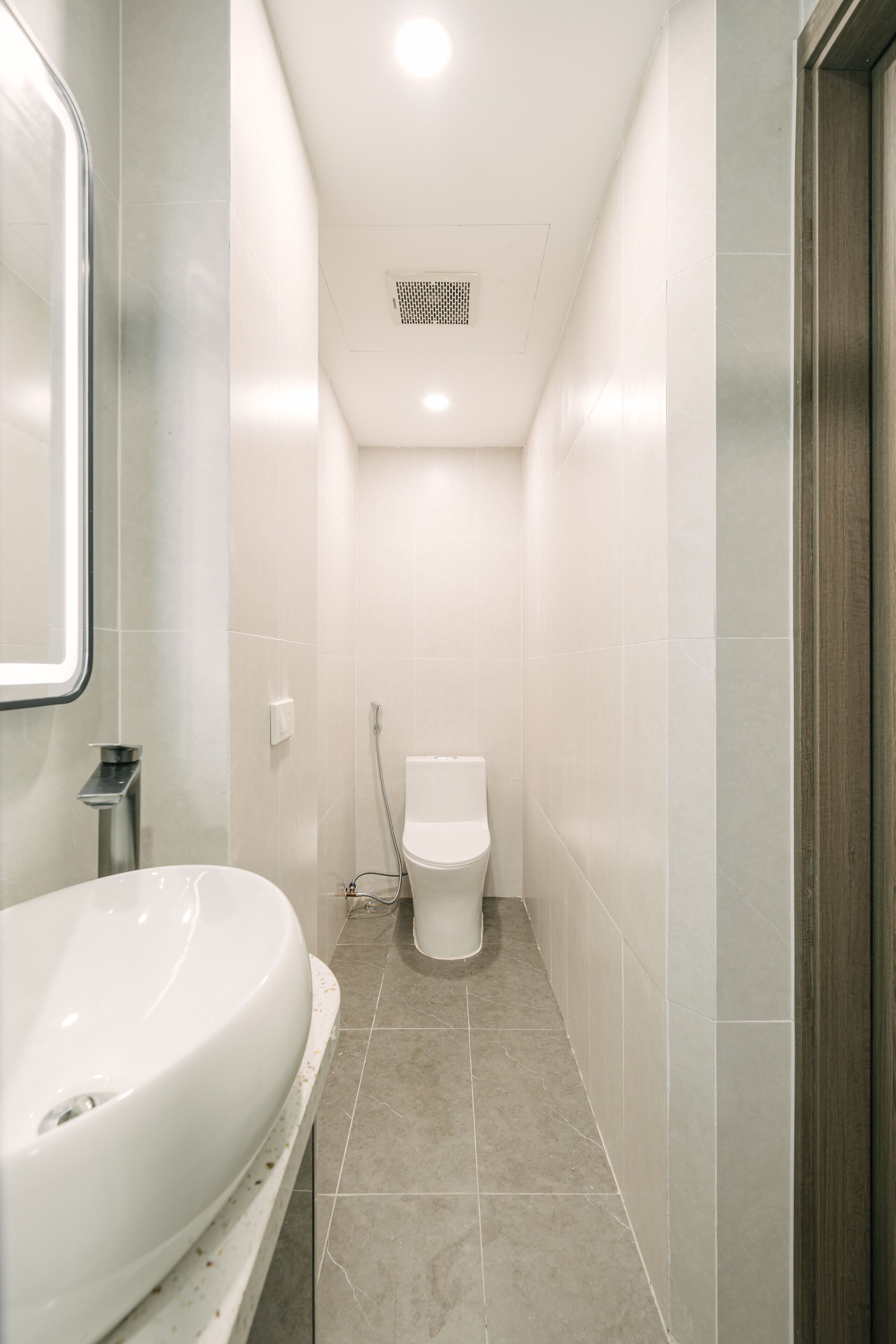 A modern bathroom with a large white sink, a toilet, and a shower area.