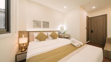 A hotel room with a large bed, a bedside table with a lamp, a mirror, and a wooden wardrobe.