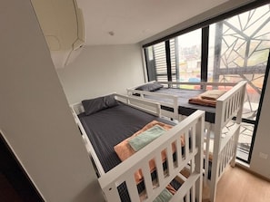 A room with bunk beds, a window with a view, and a white ceiling.