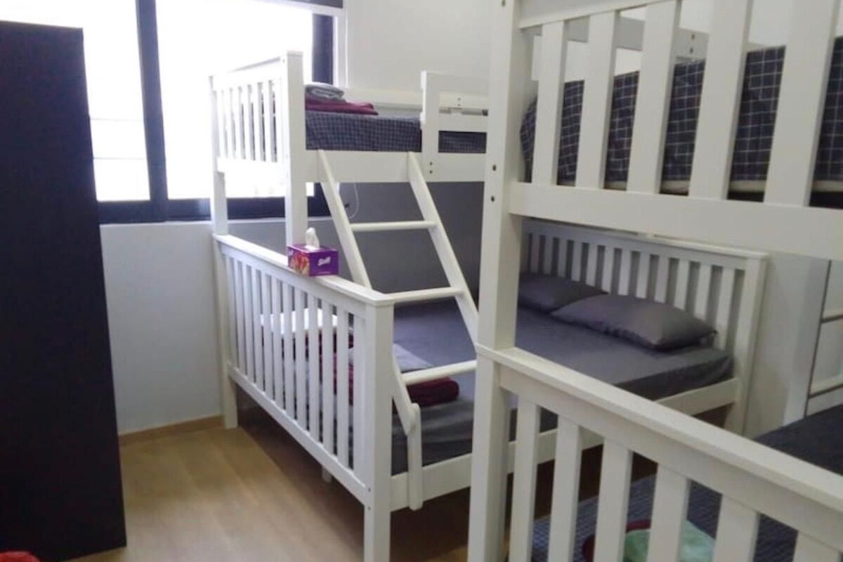 A bunk bed room with a window, a door, and a small table with a tissue box.