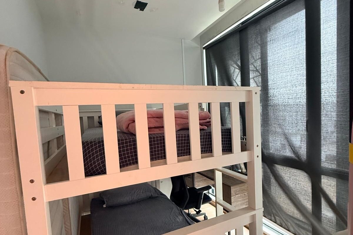 A bunk bed with a white frame, a ceiling fan, and a window with blinds.