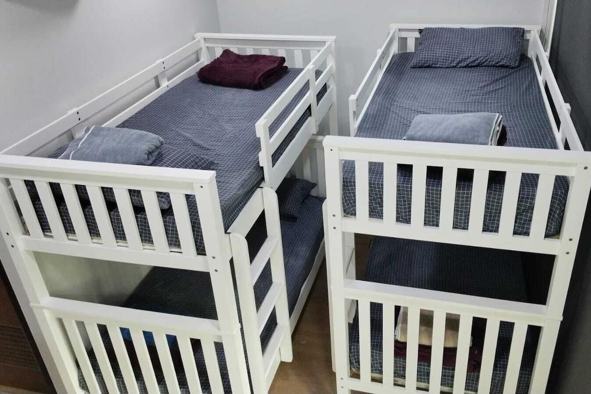 Dos literas con barandillas blancas y ropa de cama gris.