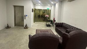 Tilava aula, jossa on sohvaryhmä, hissi ja lasiovi, joka johtaa ruokailutilaan.