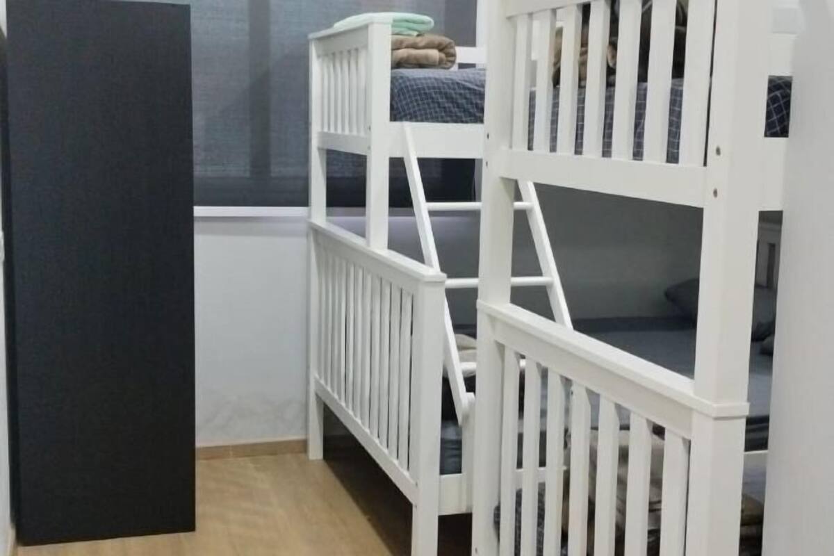 Una habitación con dos camas individuales blancas, una ventana y una puerta.