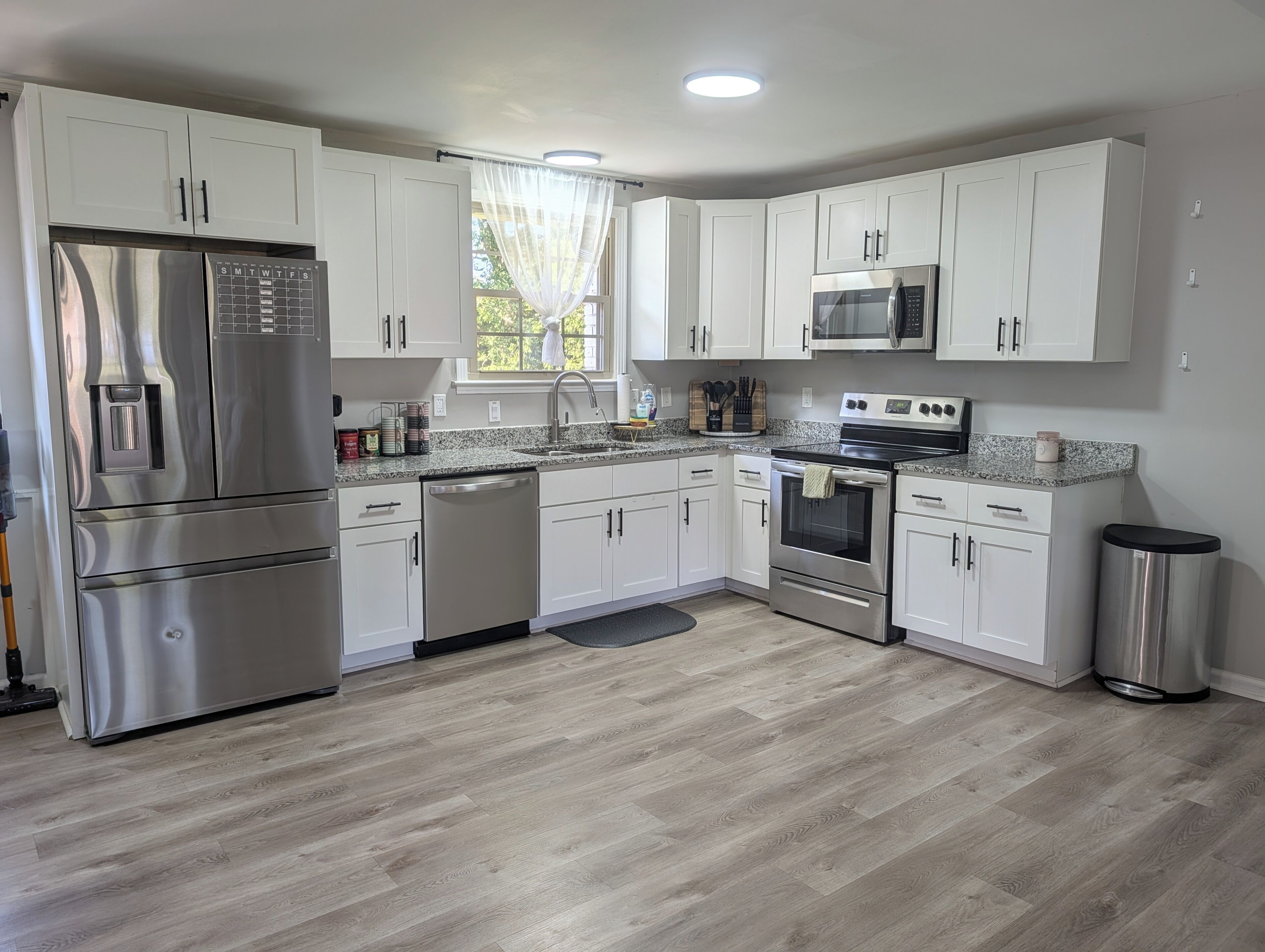 A modern kitchen with white cabinets, stainless steel appliances, and a granite countertop.