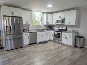 Una cocina moderna con armarios blancos, electrodomésticos de acero inoxidable y encimera de granito.