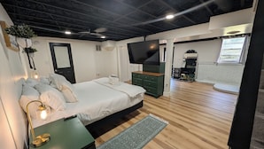 A modern bedroom with a bed, bedside lamp, and a TV. - Big Pet Friendly Home Near Ft Campbell (Clarksville)