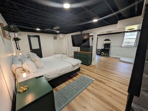 A modern bedroom with a bed, bedside lamp, and a TV. - Big Pet Friendly Home Near Ft Campbell (Clarksville)