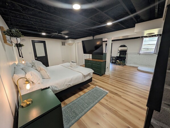 Un dormitorio moderno con cama, lámpara de noche y televisor.
