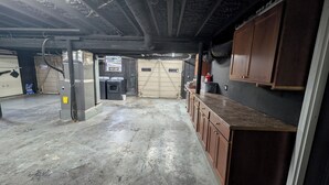 Een garage met een betonnen vloer, houten kasten, een wasmachine en een garageklep.