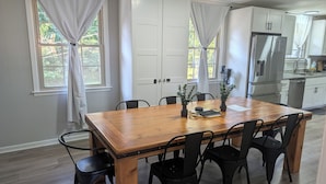 A dining area with a wooden table, black chairs, and white curtains. - Big Pet Friendly Home Near Ft Campbell (Clarksville)