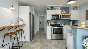A modern kitchen with white cabinetry, a wooden bar counter, and a tiled backsplash. - Beachfront Escape w Balcony+Pool (Hilton Head Island)