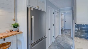 A modern kitchen with white cabinetry, a stainless steel refrigerator, and a wooden countertop with a plant. - Beachfront Escape w Balcony+Pool (Hilton Head Island)