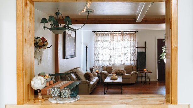 Una sala de estar acogedora con techo de madera, un sofá, una mesa de centro y una lámpara.