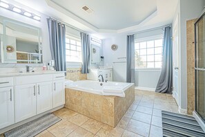A spacious bathroom with a large bathtub, a separate shower area, and a vanity with a mirror.