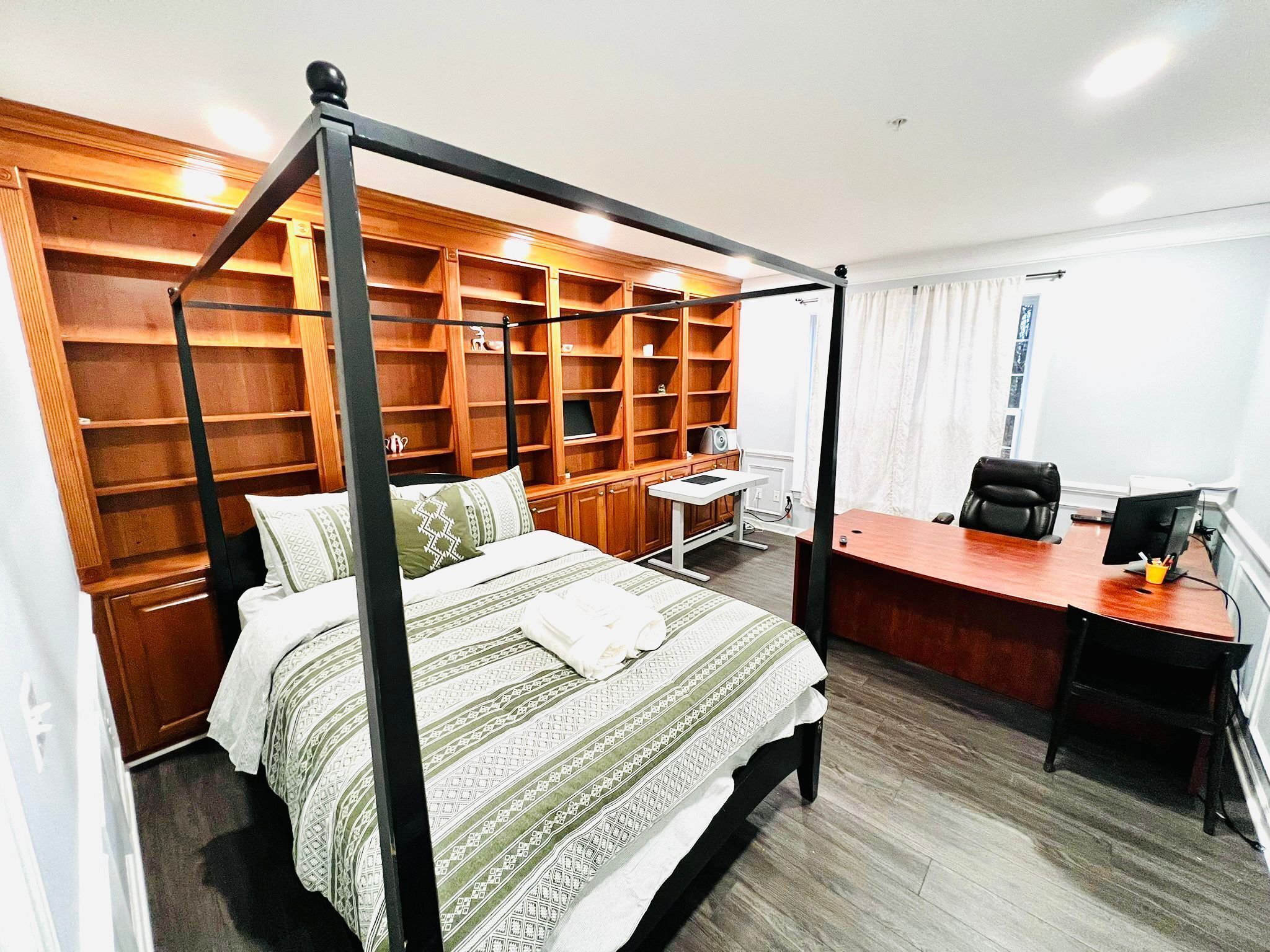 Ein Schlafzimmer mit Himmelbett, Schreibtisch inklusive Computer und einer eingebauten Holzausstattung.