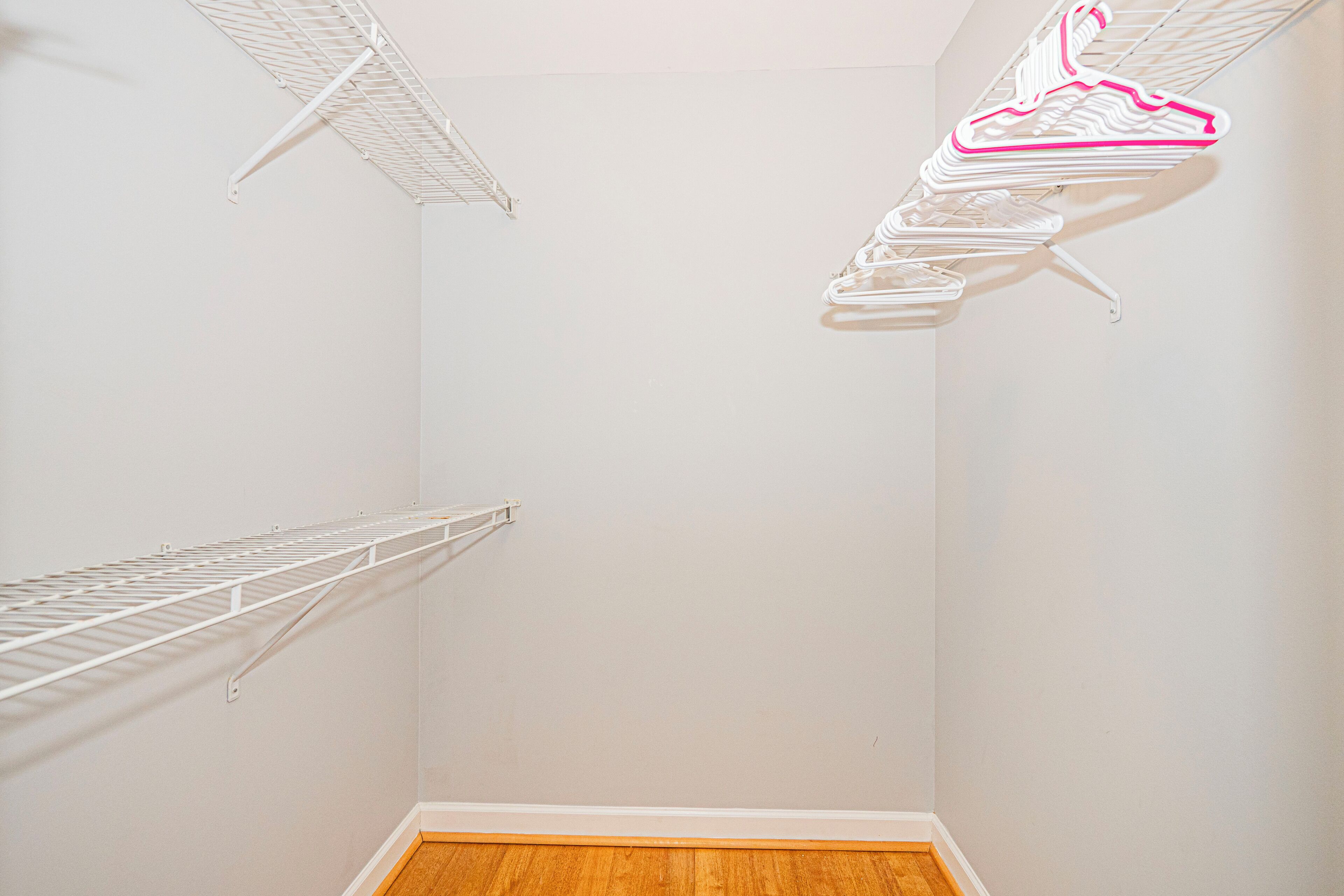 Una habitación con piso de madera, paredes blancas y techo con estructura enrejada blanca.