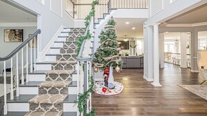 A staircase with a Christmas tree and garlands, leading to a second floor.