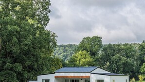 Ein modernes Einfamilienhaus mit Flachdach, großen Fenstern und einer überdachten Veranda.