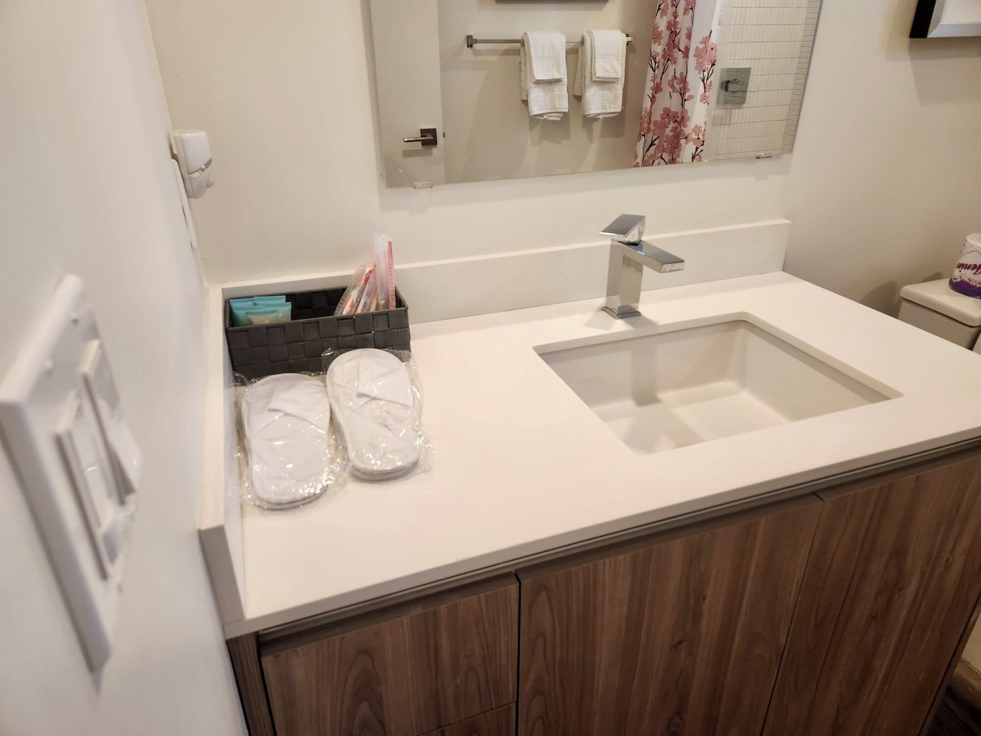 A bathroom with a white sink, wooden cabinets, a mirror, and a shower curtain.