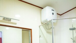 Un baño con ducha de vidrio, un lavabo con espejo y una planta en la encimera.