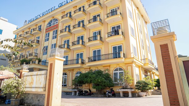 Un hotel de varios pisos con balcones, un letrero que dice “PHARIN HOTEL GIÂN KHÃU 2” y varias plantas en macetas.