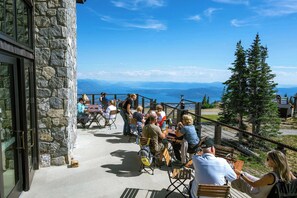 An outdoor seating area with stone walls, tables, and chairs, overlooking a scenic view.
