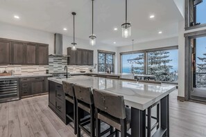 Una cocina moderna con una isla grande, armarios de madera oscura e iluminación colgante.