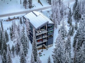 A modern multi-story building surrounded by snow-covered trees.