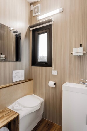 Un baño moderno con inodoro, lavamanos y espejo.