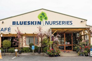 Un edificio con letreros de 'Blueskin Nurseries' y un área de entrada cubierta con plantas en macetas.