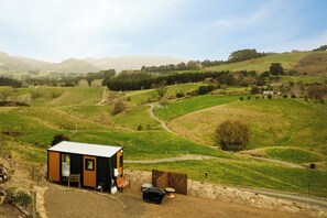 Una cabaña pequeña y moderna con una habitación, un porche y un comedor.