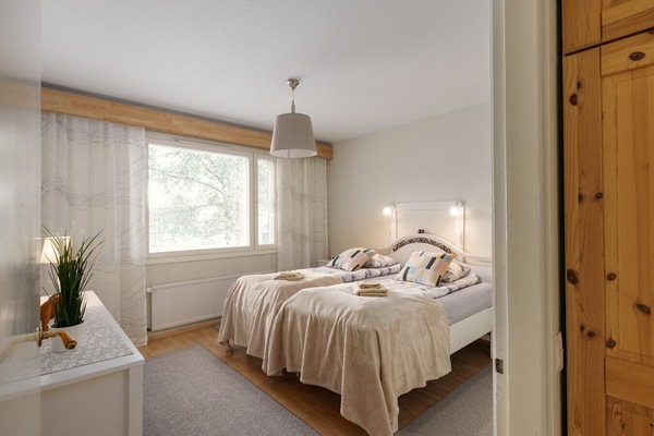 Bright and cozy bedroom featuring two single beds pushed together to form a large sleeping space. The room is decorated with soft, neutral tones and colorful pillows for a welcoming atmosphere.