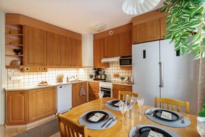 Eine moderne Küche mit Holzausstattung, einem Esstisch für vier Personen und einem Kühlschrank.