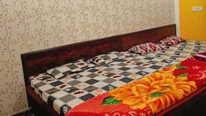 A bed with a floral quilt, a wooden headboard, and a patterned wall.