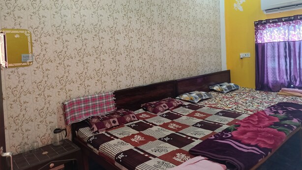 A bedroom with floral wallpaper, a bed with a patterned bedspread, a ceiling fan, and an air conditioning unit.