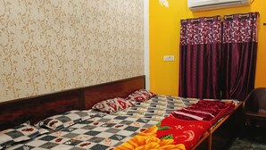 A bedroom with a bed, a ceiling fan, an air conditioner, and a window with curtains.