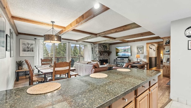 A spacious kitchen with granite countertops, wooden cabinets, and a stone fireplace. - Breck Condo | Private Balcony & Trail Access (Breckenridge)