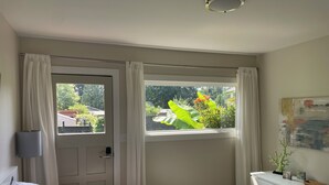 A bedroom with a bed, a dresser, a window with curtains, and a door.