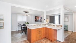 A modern kitchen with a central island, wooden cabinets, and a dining area with chairs and a table.